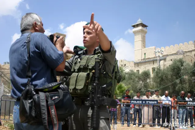 An Israeli soldier stands guard as Palestinians perform the second friday prayer of Islam's holy fasting month of Ramadan outside the Ibrahimi mosque, or the Tomb of the Patriarchs, in the divided West Bank city of Hebro...