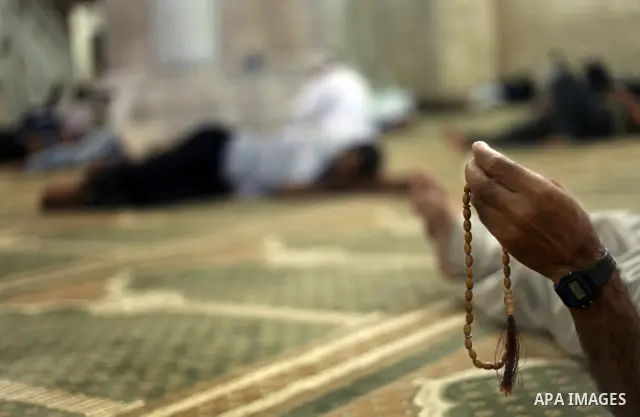 Palestinian man rest as others pray and read the Koran in a mosque during the holy month of Ramadan in Central of Gaza City on 12 August 2011. Muslims around the world are observing the holy fasting month of Ramadan in w...