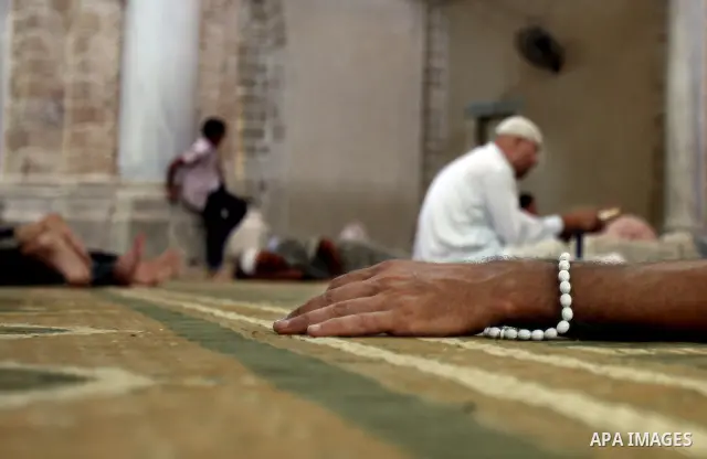 Palestinian man rest as others pray and read the Koran in a mosque during the holy month of Ramadan in Central of Gaza City on 12 August 2011. Muslims around the world are observing the holy fasting month of Ramadan in w...
