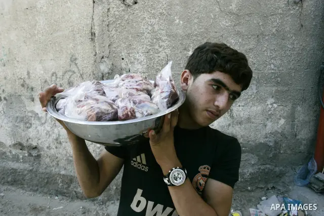 A Palestinian boy participates in the distribution of meat on the homes of the poor and needy on the thirteenth day at the occasion of the holy fasting month of Ramadan in Rafah, southern Gaza Strip on Aug. 13, 2011. whe...