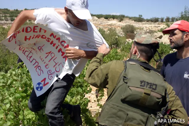 Israeli soldiers scuffle with Palestinian, Israeli and foreign activists during a demonstration against the cof farm land to be used in the construction of Jewish settlements near the existing Israeli settlement of Karmi...