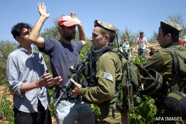 Israeli soldiers scuffle with Palestinian, Israeli and foreign activists during a demonstration against the cof farm land to be used in the construction of Jewish settlements near the existing Israeli settlement of Karmi...