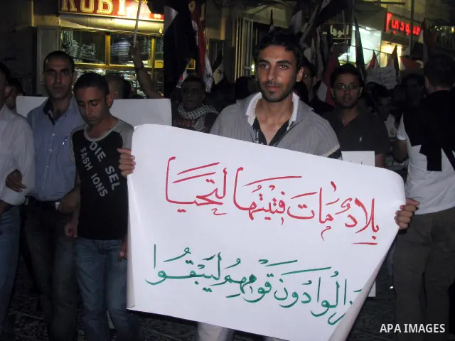 Palestinians hold Syrian flags as they join a demonstration in the West Bank city of Ramallah on Aug. 14, 2011 in support of the Syrian opposition . At least 23 people were killed 14 August when the Syrian army attacked...