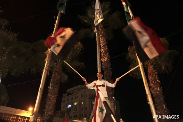 Palestinians hold Syrian flags as they join a demonstration in the West Bank city of Ramallah on Aug. 14, 2011 in support of the Syrian opposition . At least 23 people were killed 14 August when the Syrian army attacked...