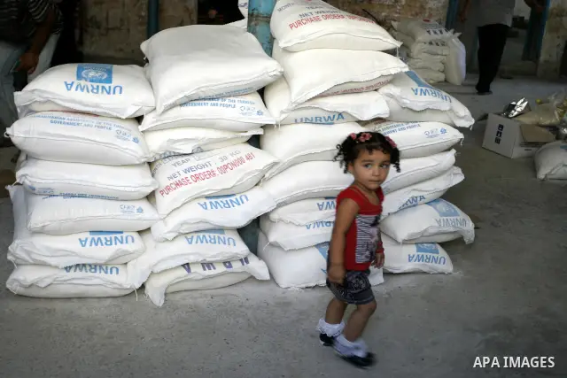 A Palestinian girl walks near food aids receiving from the United Nations Relief and Works Agency (UNRWA) at the Rafah refugee camp, in the southern Gaza Strip on August 15, 2011. USAID halted humanitarian assistance to...