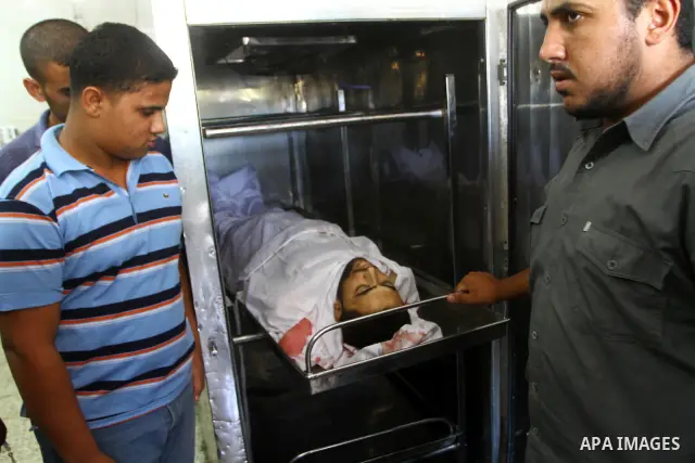 Palestinian relatives stand next to the body of Hamas militant Moussa Shtewi, 29, at the morgue in a hospital in Gaza City, Tuesday, on Aug. 16, 2011. Israeli aircraft struck five targets in the Hamas-ruled Gaza Strip on...
