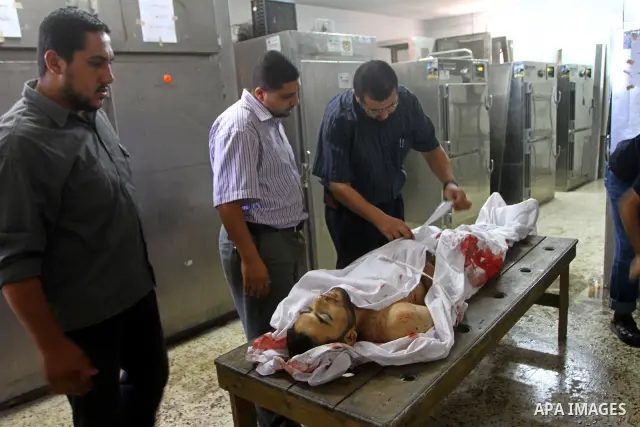 Palestinian relatives stand next to the body of Hamas militant Moussa Shtewi, 29, at the morgue in a hospital in Gaza City, Tuesday, on Aug. 16, 2011. Israeli aircraft struck five targets in the Hamas-ruled Gaza Strip on...