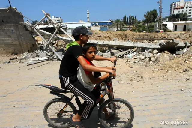 Palestinian children ride the bicycle at the site of an Israeli air strike in Gaza City on August 16, 2011 after one Palestinian was killed and seven injured by overnight Israeli air strikes across the Gaza Strip, Palest...