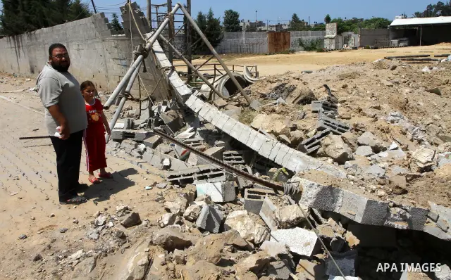 Palestinians stand at the site of an Israeli air strike in Gaza City on August 16, 2011 after one Palestinian was killed and seven injured by overnight Israeli air strikes across the Gaza Strip, Palestinian medics said....