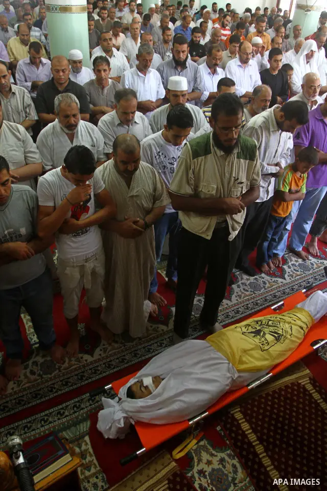 Palestinian mourners pray on the body of Saad al-Majdalali before his funeral in the central Gaza Strip refugee camp of Nusseirat on August 17, 2011 a day after Israeli troops shot and killed him as he came near to the b...