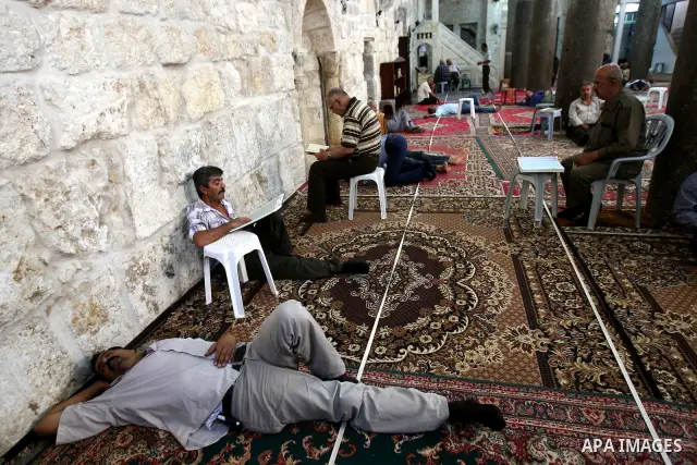Palestinian Muslims rest as others pray and read the holy Koran at a Mosque during the holy month of Ramadan in the West Bank city of Nablus on Aug. 17, 2011. Muslims around the world are observing the holy fasting month...