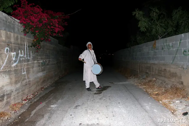 A Palestinian man 'Mesaharaty' uses a traditional drum to wake up people for their Suhoor, in the village of Balata in the West Bank city of Nablus, on, Aug .18, 2011. Muslims throughout the world are celebrating the hol...
