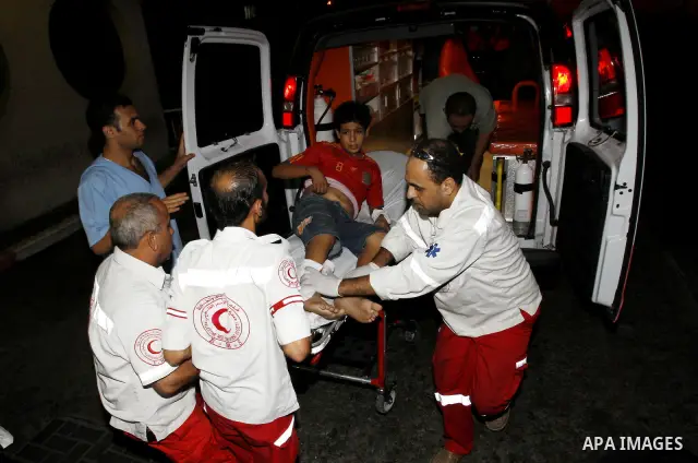 Palestinians wheel a wounded boy following an Israeli attack in Gaza City on August 19, 2011. Photo by Mahmud Nassar