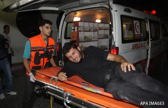 Palestinians wheel a wounded man following an Israeli attack in Gaza City on August 19, 2011. Photo by Mahmud Nassar