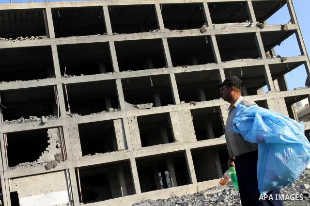 A Palestinian man stands past a damaged government building after an Israeli air strike in Gaza August 19, 2011. Israeli aircraft struck Hamas security installations in Gaza on Friday, killing at least one Palestinian, i...