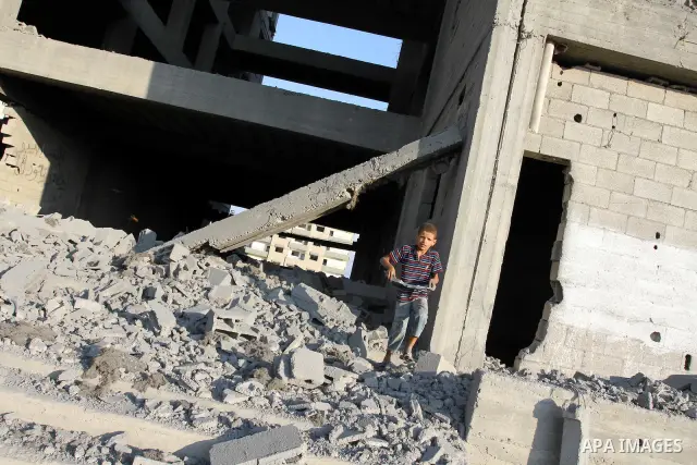 A Palestinian boy stands past a damaged government building after an Israeli air strike in Gaza August 19, 2011. Israeli aircraft struck Hamas security installations in Gaza on Friday, killing at least one Palestinian, i...