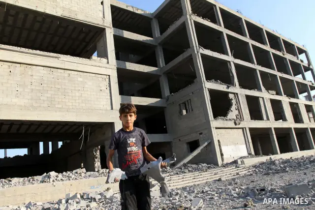 A Palestinian boy stands past a damaged government building after an Israeli air strike in Gaza August 19, 2011. Israeli aircraft struck Hamas security installations in Gaza on Friday, killing at least one Palestinian, i...