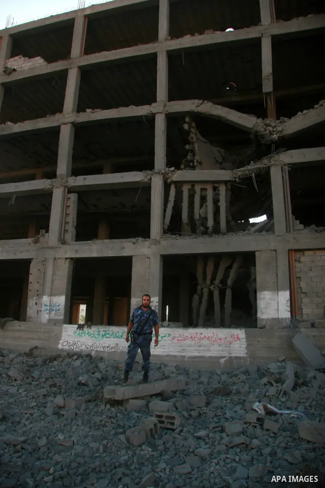A Hamas policeman stands past a damaged government building after an Israeli air strike in Gaza August 19, 2011. Israeli aircraft struck Hamas security installations in Gaza on Friday, killing at least one Palestinian, i...