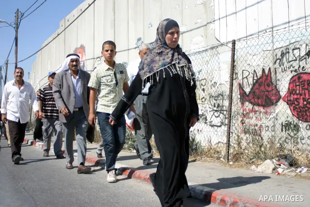 Palestinian Muslims walk through an Israeli checkpoint on the outskirts of the West Bank city of Bethlehem on August 19, 2011 as they wait to cross into Jerusalem on their way to pray at the Al Aqsa Mosque on the third F...