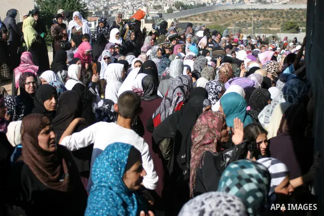 Palestinian Muslims wait at an Israeli checkpoint on the outskirts of the West Bank city of Bethlehem on August 19, 2011 as they wait to cross into Jerusalem to attend on their way to pray at the Al Aqsa Mosque on the th...