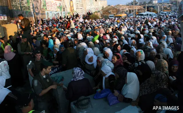 Palestinian women wait to cross the Qalandia checkpoint on their way to pray at the Al Aqsa Mosque on the third Friday of the Muslim holy month of Ramadan, at the Qalandia checkpoint between the West Bank city of Ramalla...