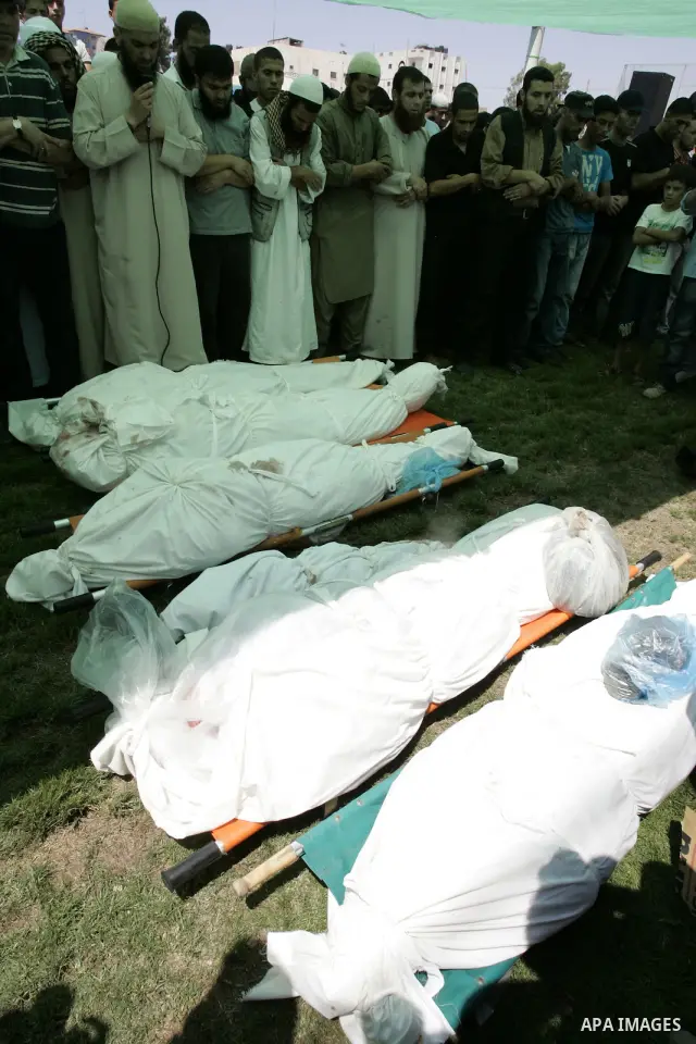 Palestinians pray near the bodies of people killed in Israeli air strikes during a funeral in the Rafah refugee camp, southern Gaza Strip, on August 19, 2011. Israeli fighter jets bombed Gaza, killing a teenager and inju...