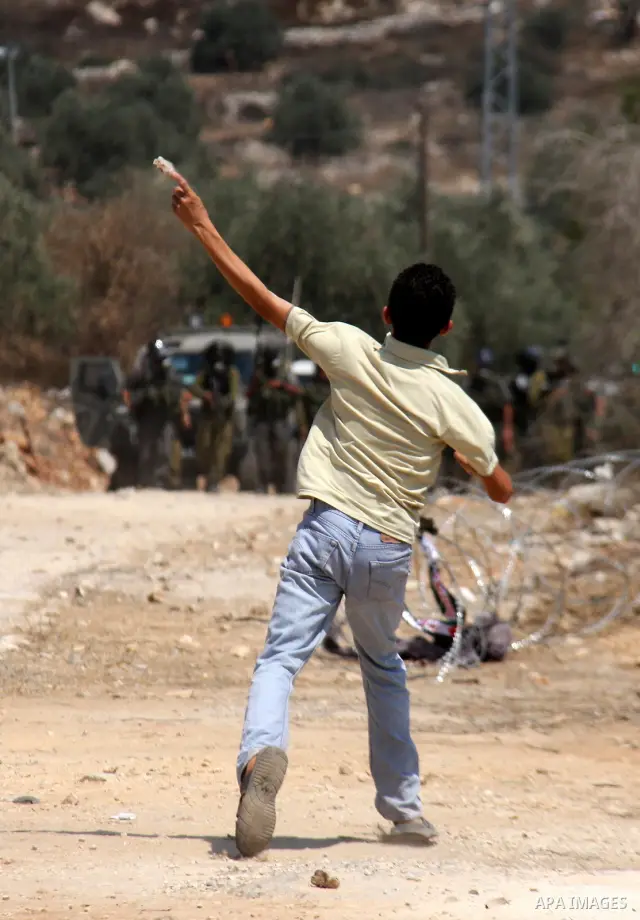 A Palestinian demonstrator throws stones toward Israeli forces during clashes following a protest against the closure of a road during the second Intifada by Jewish settlers from the nearby settlement of Kadumim on Augus...