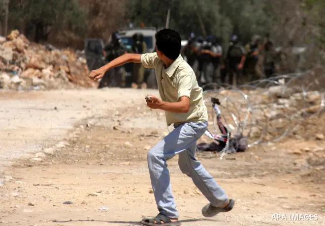 A Palestinian demonstrator throws stones toward Israeli forces during clashes following a protest against the closure of a road during the second Intifada by Jewish settlers from the nearby settlement of Kadumim on Augus...