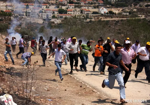 Palestinian demonstrators run as Israeli forces start to fire tear gas during clashes following a protest against the closure of a road during the second Intifada by Jewish settlers from the nearby settlement of Kadumim...