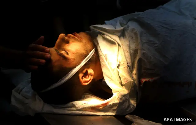 Palestinian men carry the body of Mohammed Enaya at the mortuary of Al-Shifa hospital after he was killed when the Israeli air force targeted an area in the eastern part of Gaza City on August 19, 2011. Photo by Ashraf A...
