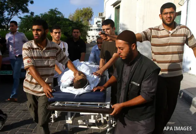 Palestinian men carry the body of Mohammed Enaya at the mortuary of Al-Shifa hospital after he was killed when the Israeli air force targeted an area in the eastern part of Gaza City on August 19, 2011. Photo by Ashraf A...