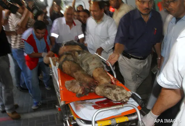 Palestinian men carry the body of Mohammed Enaya at the mortuary of Al-Shifa hospital after he was killed when the Israeli air force targeted an area in the eastern part of Gaza City on August 19, 2011. Photo by Ashraf A...