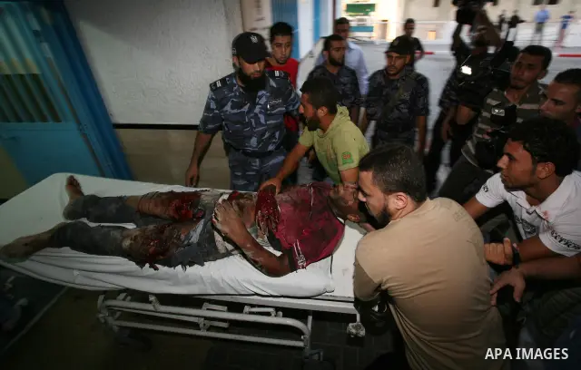 Palestinians carry a wounded boy into Al-Shifa hospital following Israeli air attacks, in Gaza City, Gaza Strip, 19 August 2011. Photo by Mahmud Nassar