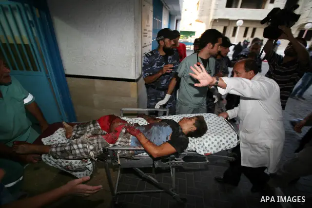 Palestinians carry a wounded boy into Al-Shifa hospital following Israeli air attacks, in Gaza City, Gaza Strip, 19 August 2011. Photo by Mahmud Nassar