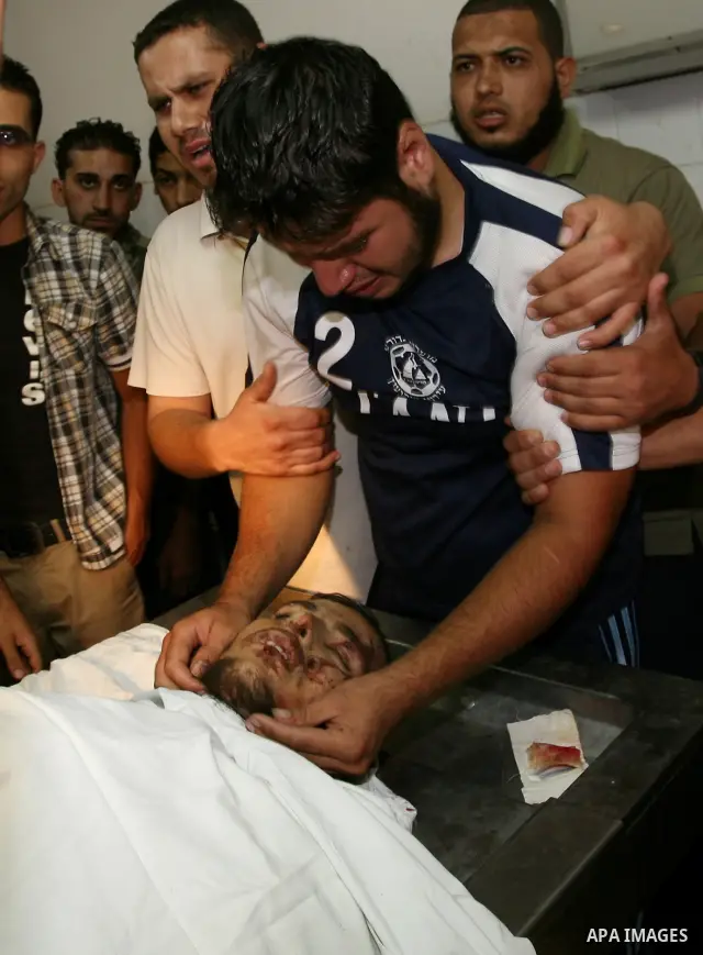 Palestinian men gather around the body of Mohammed Enaya at the mortuary of Al-Shifa hospital after he was killed when the Israeli air force targeted an area in the eastern part of Gaza City on August 19, 2011. Photo by...