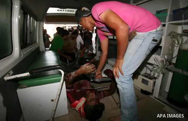 Palestinians carry a wounded boy into Al-Shifa hospital following Israeli air attacks, in Gaza City, Gaza Strip, 19 August 2011. Photo by Mahmud Nassar