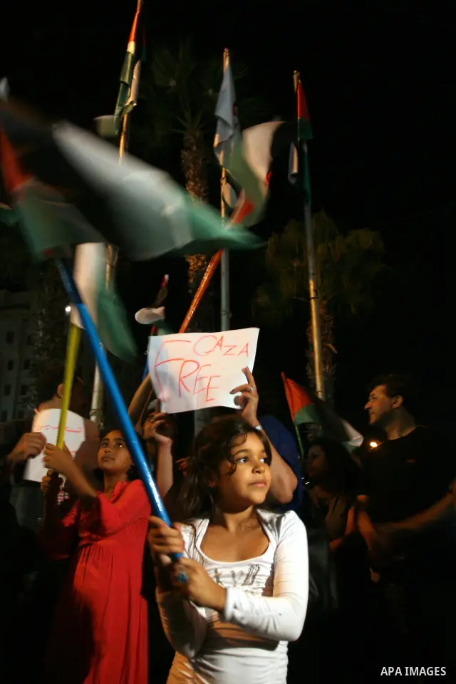 Palestinians wave with their national flag and hold placards during a protest in solidarity with the people in Gaza Strip, in the West Bank city of Ramallah on August 19,2011. Israel struck Gaza with two days of air stri...