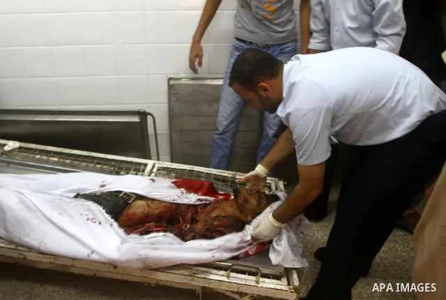 Palestinian men gather around the bodies of Emad Abu Abda and Anwar Isleem at the mortuary of Al-Aqsa hospital after they were killed when the Israeli air force targeted an area in the central Gaza Strip on August 19, 20...