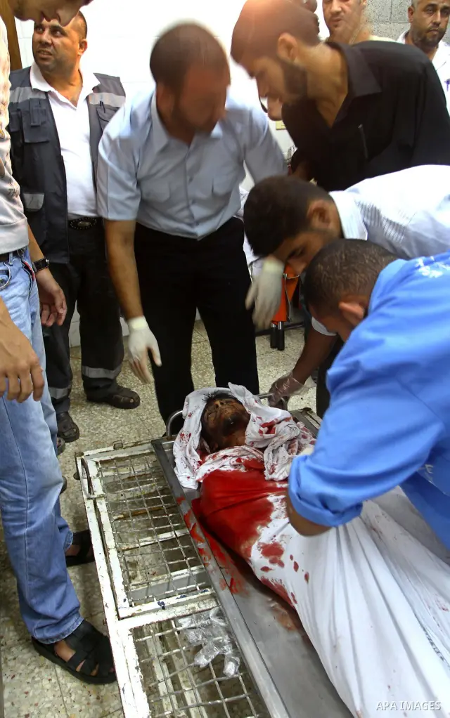 Palestinian men gather around the bodies of Emad Abu Abda and Anwar Isleem at the mortuary of Al-Aqsa hospital after they were killed when the Israeli air force targeted an area in the central Gaza Strip on August 19, 20...