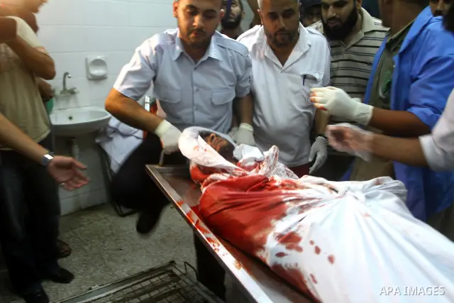 Palestinian men gather around the bodies of Emad Abu Abda and Anwar Isleem at the mortuary of Al-Aqsa hospital after they were killed when the Israeli air force targeted an area in the central Gaza Strip on August 19, 20...