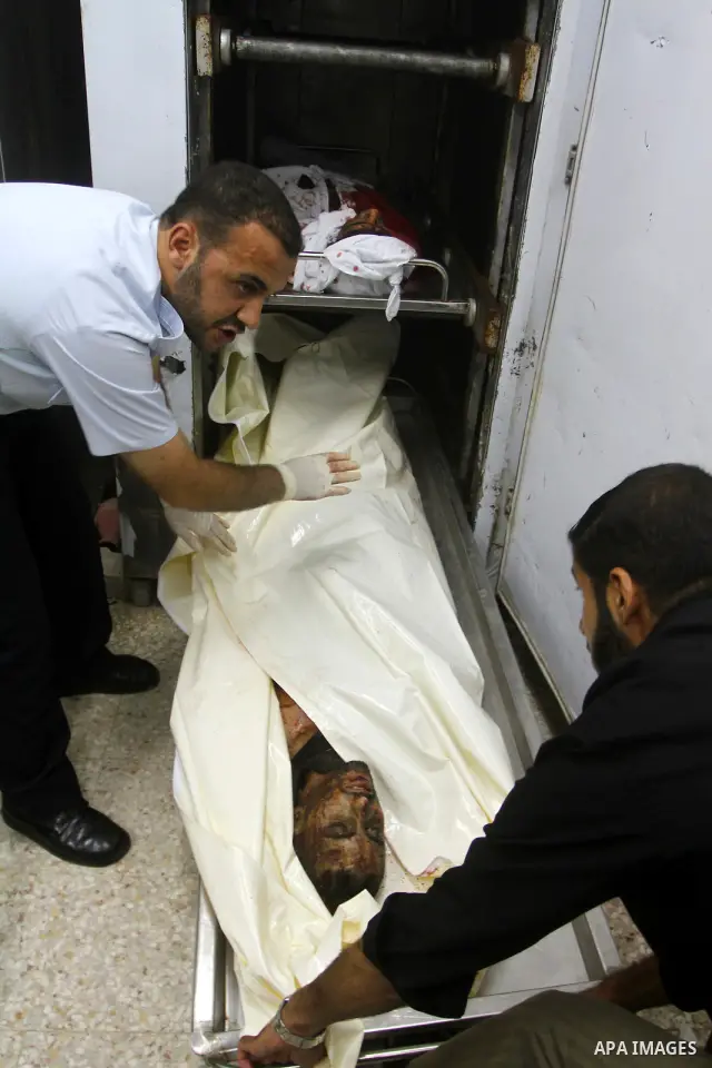 Palestinian men gather around the bodies of Emad Abu Abda and Anwar Isleem at the mortuary of Al-Aqsa hospital after they were killed when the Israeli air force targeted an area in the central Gaza Strip on August 19, 20...