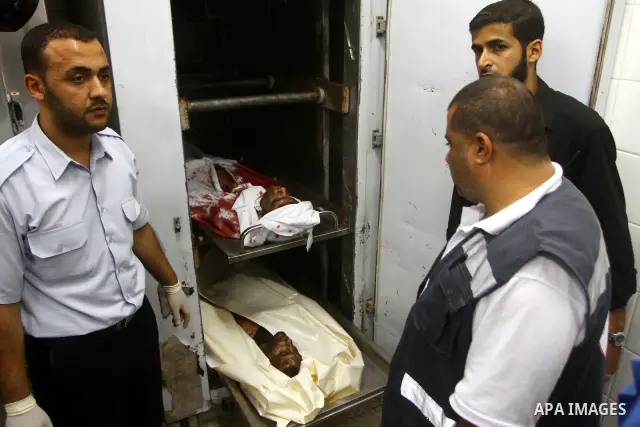 Palestinian men gather around the bodies of Emad Abu Abda and Anwar Isleem at the mortuary of Al-Aqsa hospital after they were killed when the Israeli air force targeted an area in the central Gaza Strip on August 19, 20...