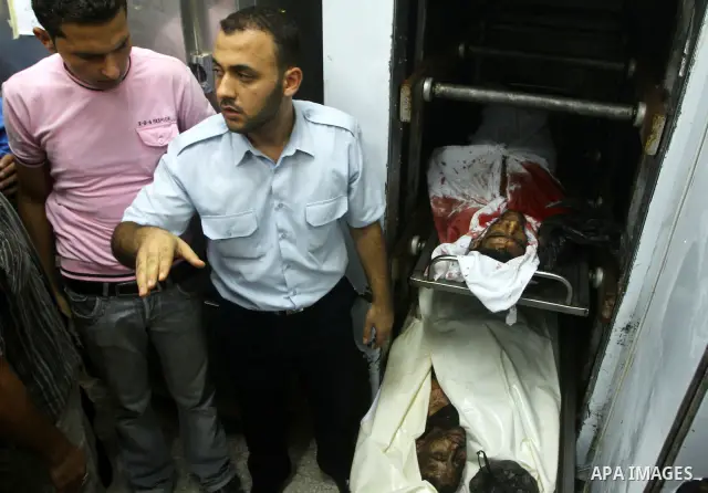 Palestinian men gather around the bodies of Emad Abu Abda and Anwar Isleem at the mortuary of Al-Aqsa hospital after they were killed when the Israeli air force targeted an area in the central Gaza Strip on August 19, 20...