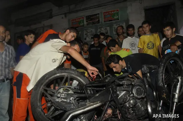 Palestinians inspect a destroyed motorcycle following an Israeli airstrike killing three Palestinian who were riding it, at the main road in Gaza City, Friday, Aug. 19, 2011. Palestinian official said that Dr. Monzer Qra...