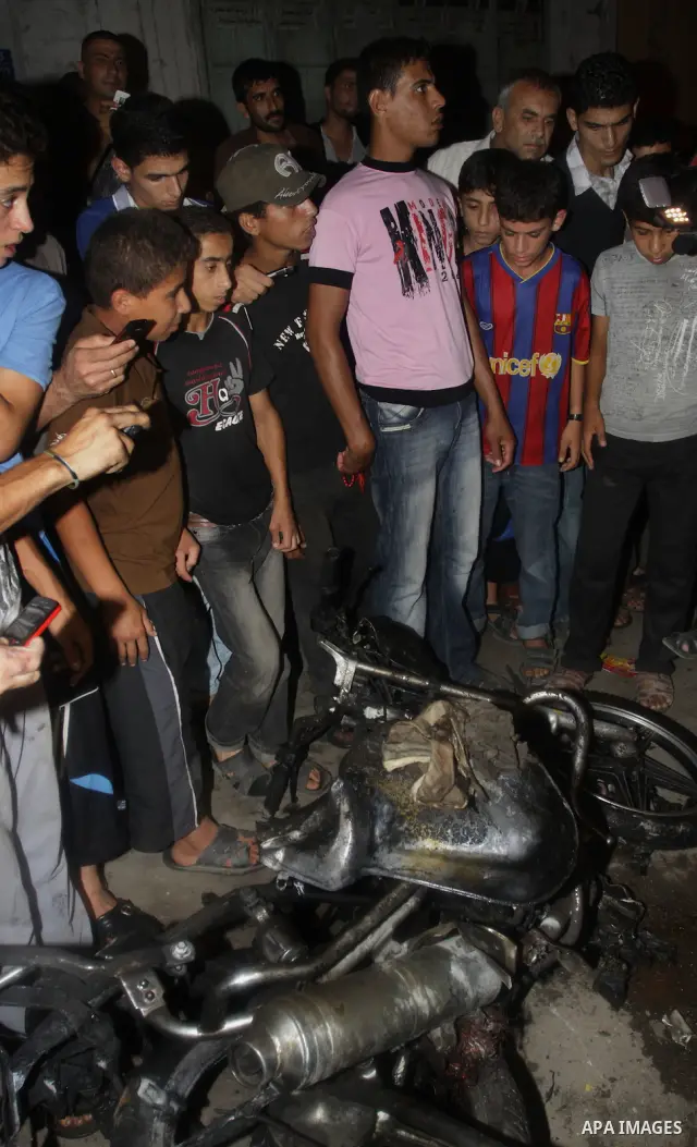 Palestinians inspect a destroyed motorcycle following an Israeli airstrike killing three Palestinian who were riding it, at the main road in Gaza City, Friday, Aug. 19, 2011. Palestinian official said that Dr. Monzer Qra...