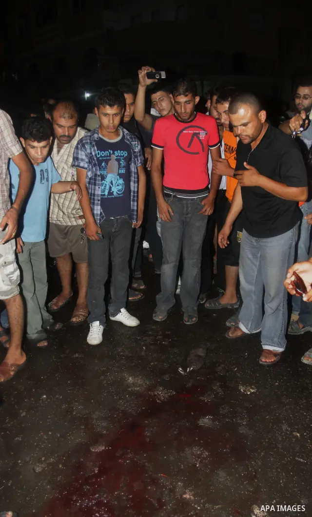 Palestinians inspect the Blood following an Israeli airstrike killing three Palestinian who were riding it, at the main road in Gaza City, Friday, Aug. 19, 2011. Palestinian official said that Dr. Monzer Qrakea, 35, and...