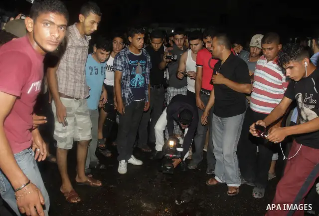 Palestinians inspect the Blood following an Israeli airstrike killing three Palestinian who were riding it, at the main road in Gaza City, Friday, Aug. 19, 2011. Palestinian official said that Dr. Monzer Qrakea, 35, and...