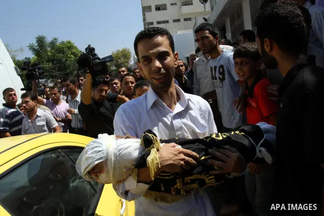 A Palestinian man carries the body of two-year-old boy Islam Qreqa during a funeral in Gaza City on August 20, 2011. Palestinians said at least nine militants have died in multiple Israeli strikes, as well as two childre...