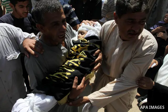 A Palestinian man carries the body of two-year-old boy Islam Qreqa during a funeral in Gaza City on August 20, 2011. Palestinians said at least nine militants have died in multiple Israeli strikes, as well as two childre...