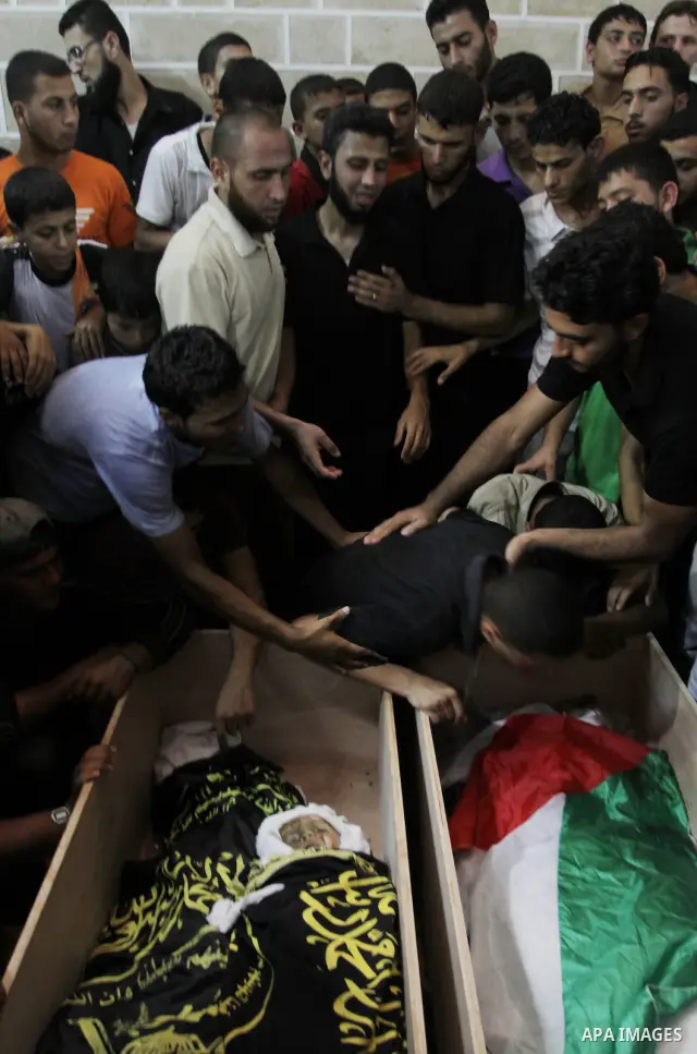 Palestinians mourn over the bodies of Moataz Qreqa, a commander of Islamic Jihad's Al-Quds Brigade, his five-year-old son Islam and his brother Munzer during their funeral in Gaza City on August 20, 2011 after all three...